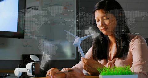 Engineer examining wind turbine model on desk with vr headset and dotted world map overlay