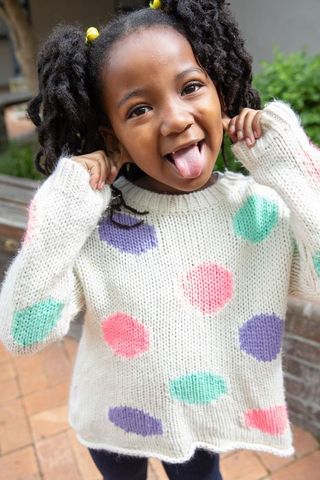 Playful young girl with polka-dot sweater