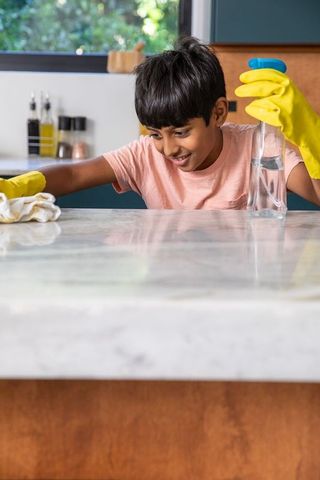 Cheerful Boy Cleaning Kitchen Counter in Warm Home Environment
