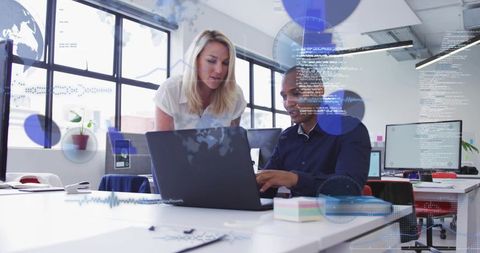 Collaborating colleagues working on laptop with data overlays in modern open-plan office