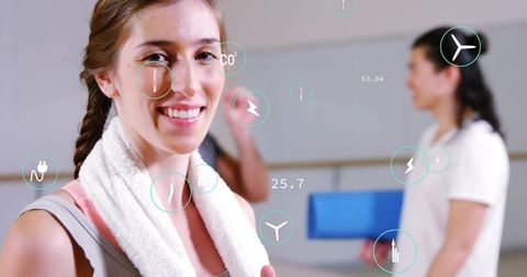 Smiling woman with towel in fitness studio with augmented reality fitness hud overlay