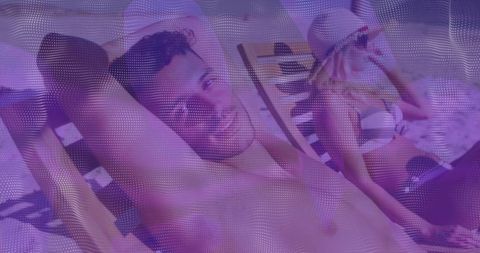 Smiling shirtless man reclining on striped lounger while woman in bikini adjusting sun hat
