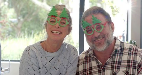 Senior Couple Wearing Festive Christmas Tree Glasses Joyfully Celebrating Holiday