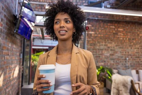 Confident woman holding coffee in modern coworking space