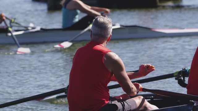 Senior men rowing boats on a river. Emphasizing teamwork, physical fitness, and healthy outdoor activities. Useful for themes related to active retirement, senior hobbyist sports, and health and wellness promotions for older adults.