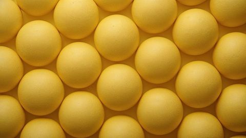 Tightly packed yellow textured spheres creating minimalist pattern