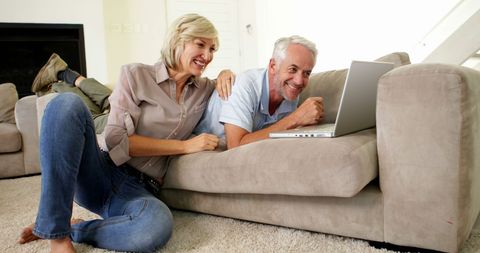 Happy Retiree Couple Enjoying Technology in Cozy Living Room