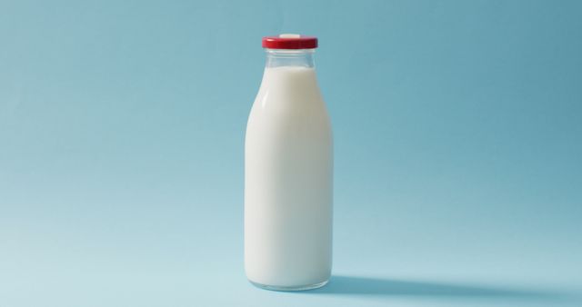 Image of glass bottle of milk on blue background. dairy products and healthy organic nutrition.