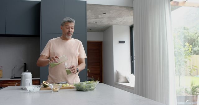 Middle-aged Man Enjoying Fresh Green Smoothie in Modern Kitchen - Download Free Stock Images Pikwizard.com