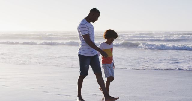 African american father and his son walking and holding hands on the beach. healthy outdoor leisure time by the sea.