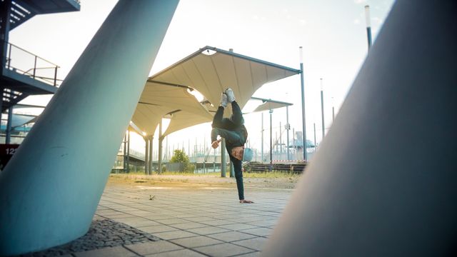 Man breakdancing in an urban park during sunset creates a dynamic and edgy feel. Suitable for use in promoting urban culture, street dance, and active lifestyle programs. Ideal for advertisements, editorial uses, social media posts, and fitness-related content.