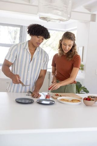 Young couple preparing healthy snack on sunlit modern kitchen island