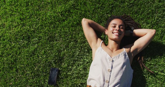 Happy woman with dreadlocks relaxing on grass in summer sun - Download Free Stock Images Pikwizard.com