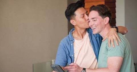 Diverse Gay Couple Laughing Together with Smartphone at Home