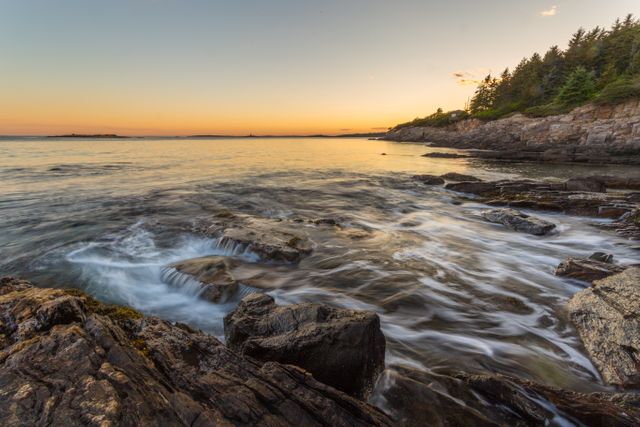 Beautiful coastal landscape with rocky shoreline and gently crashing waves under sunset sky. Ideal for representing tranquility, natural beauty, and peaceful outdoor scenes. Useful for travel magazines, nature blogs, relaxation-themed content, and landscape photography enthusiasts.