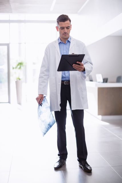Doctor standing with clipboard in corridor at hospital