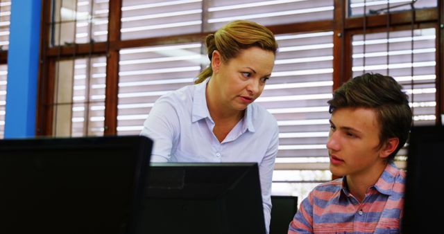 Teacher assisting students in computer class at school