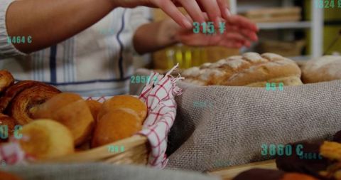 Woman arranging artisan bread and pastries on rustic market counter with teal price tags