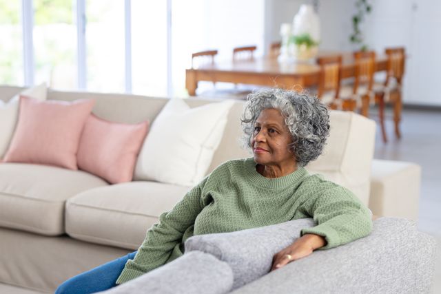 Happy senior african american woman relaxing on sofa in living room, copy space. Retirement, relaxation, senior health, happiness, inclusivity and senior lifestyle concept.