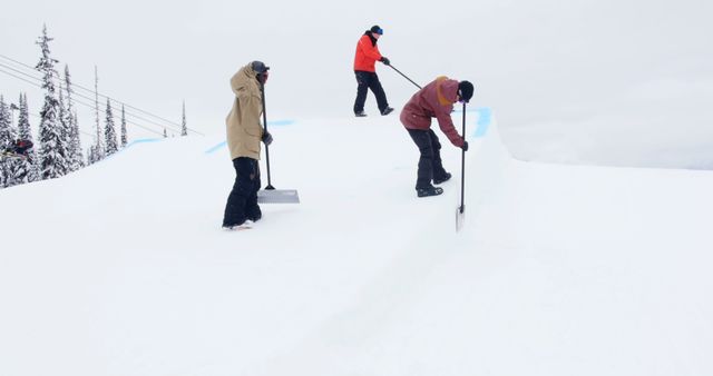 Three workers are using equipment to smooth a snowboarding slope, ensuring it is ready for a competition or event. This setting is ideal for illustrating the importance of team effort and maintenance in winter sports. It can be used for articles on event preparation, winter sports, and teamwork.