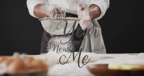 Baker sifting flour over dough on moody kitchen counter with new year new me overlay