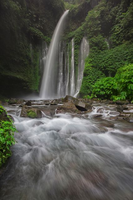 Serene Waterfall Cascading into River Surrounded by Lush Greenery - Download Free Stock Photos Pikwizard.com