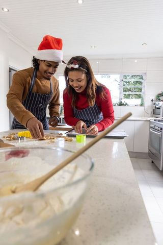 Asian couple baking festive christmas cookies in bright modern kitchen, smiling together