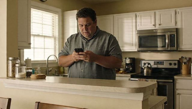 Middle-aged man checking smartphone in cozy kitchen morning routine