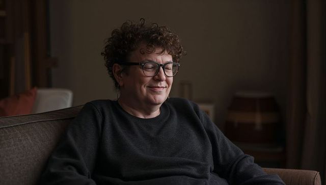 Middle-aged man relaxing on sofa wearing glasses embracing cozy home comfort