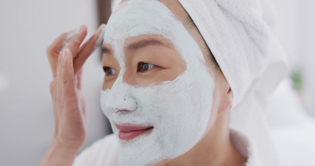 Image of happy asian woman in robe with moisturizing mask. Beauty, skincare and spending time at home concept.