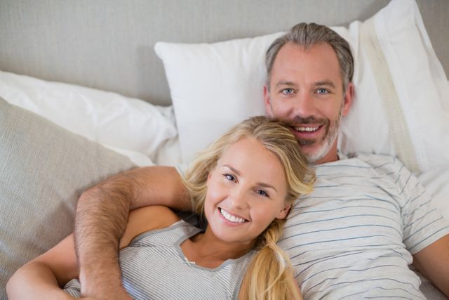 Portrait of happy couple relaxing on bed in bedroom at home