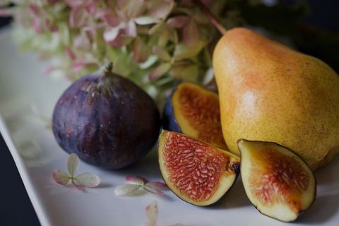 Fresh pear and figs with blossoms on white plate