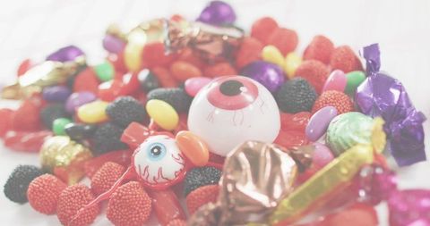 Spooky eyeball lollipops mingling with colorful halloween candy assortment on white table