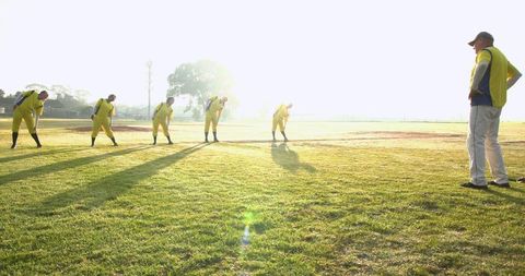 Baseball Team Stretching with Coach Observing at Sunrise
