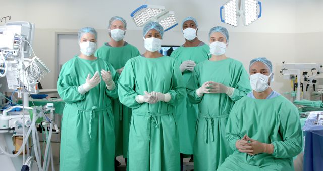 Surgical team standing in an operating room, wearing masks, gloves, and green scrubs. Medical equipment and lighting fixtures are visible in the background. Can be used for articles, presentations, and educational materials related to healthcare, surgery, medical procedures, and teamwork in medical settings.