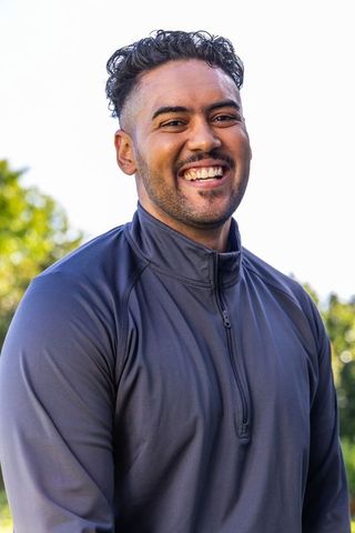 Smiling young man wearing navy quarter-zip pullover enjoying sunny outdoor bokeh portrait