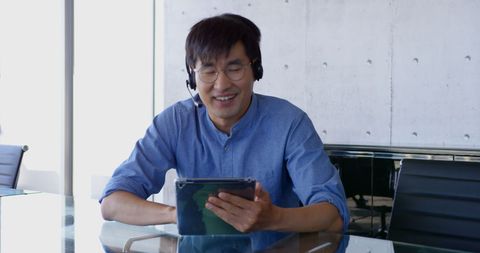 Asian Executive Interacting via Tablet in Modern Office