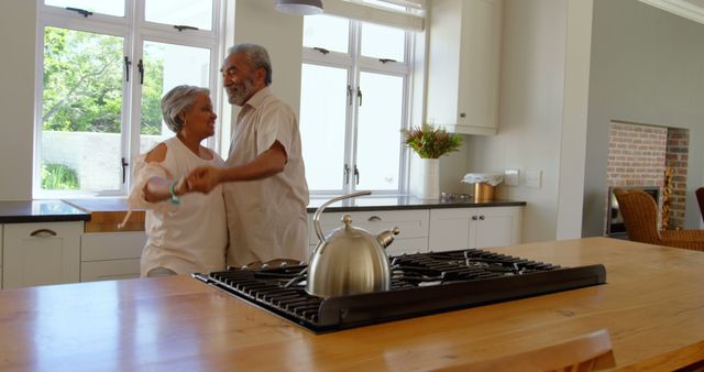 Side view of senior black couple dancing together in kitchen at comfortable home. They are smiling and holding hands 4k
