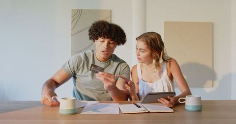 Young couple managing finances with credit card and tablet