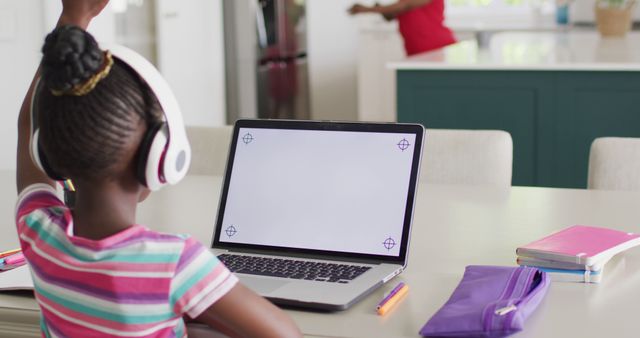African american girl in headphones raising hand in online lesson on laptop, copy space on screen. Education, learning, technology and domestic life.