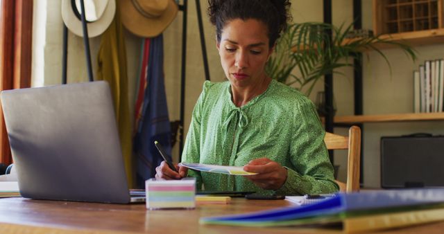 Biracial woman taking notes while working from home - Download Free Stock Photos Pikwizard.com