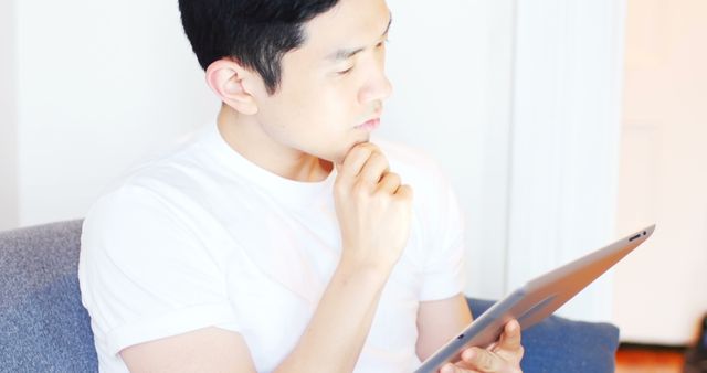 Thoughtful Young Man Using Digital Tablet at Home - Download Free Stock Images Pikwizard.com