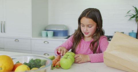 Young girl unpacking groceries in modern kitchen