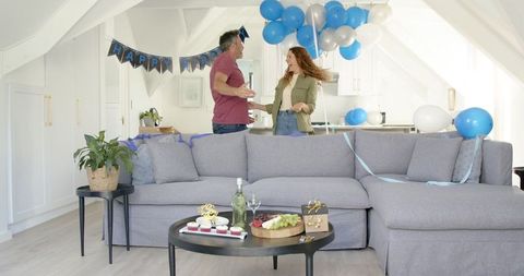 Joyful couple decorating living room for birthday celebration