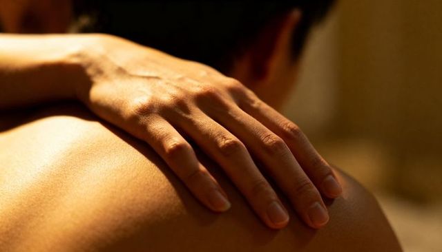 Hand resting on bare back conveying intimacy comfort warm lighting skin texture closeup