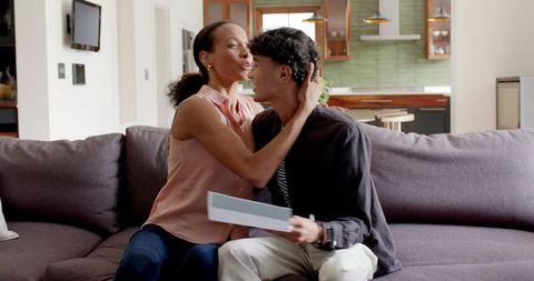 Young couple sharing affectionate moment on sofa in modern open-plan kitchen living room
