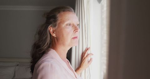 Pensive Senior Woman Gazing Out Sunlit Window