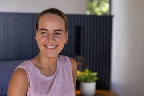 Smiling young woman in pink knit top enjoying minimalist interior and natural daylight