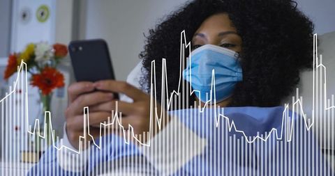 Wearing Face Mask Lying in Hospital Bed Holding Smartphone Monitoring Health Data and Recovery