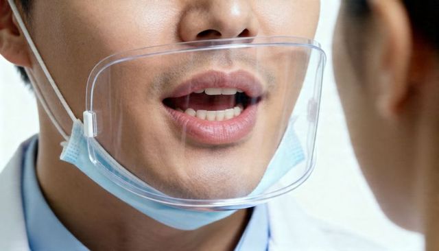 Clinician speaking through clear face shield with lowered surgical mask for clear speech